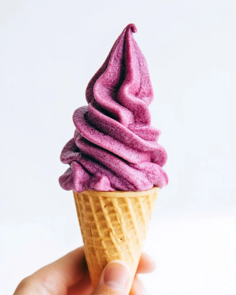 Yogur helado vegano de arándano servido en un tazón con frutas frescas.