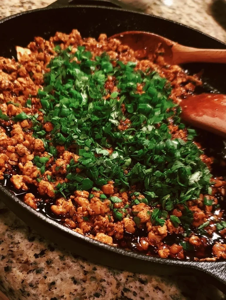 Sartén de pollo molido con miel y ajo cocinándose en la cocina