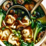 Sopa de potstickers caliente servida en un tazón con hierbas frescas.