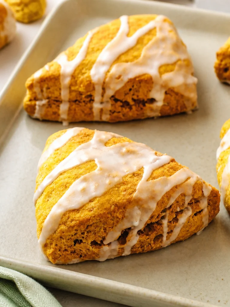 Scones de calabaza recién horneados sobre una mesa con decoración otoñal